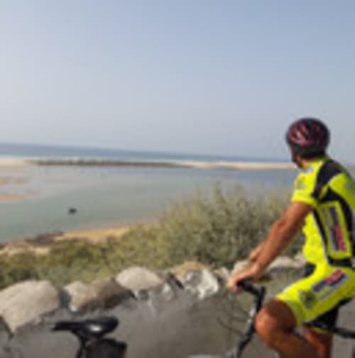Cycliste en gilet fluorescent contemplant la plage et le lagon de Santa Luzia