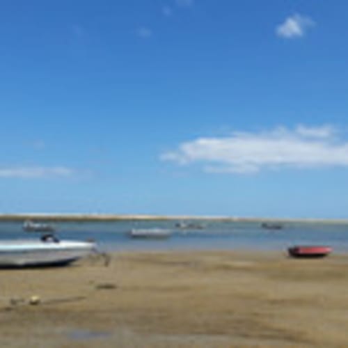 Bateaux sur la plage de sable de Santa Luzia avec un ciel bleu clair et des eaux peu profondes
