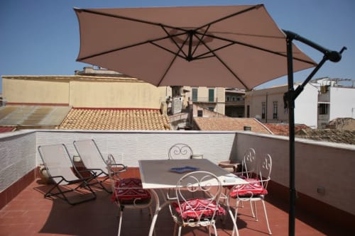 Casa Bellini rooftop terrace in Palermo with dining table, chairs, and shade umbrella overlooking city