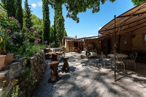 Toskanischer Innenhof des Gästehauses La Bouscatière in Moustiers-Sainte-Marie mit Pergola, rustikalen Möbeln und Blütenpflanzen