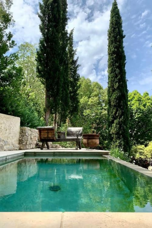 Türkisfarbener Pool in La Bouscatière in Moustiers-Sainte-Marie mit hohen Zypressen und rustikalem Innenhofambiente