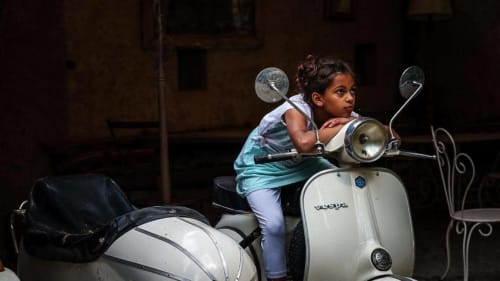 Kind auf weißem Vespa-Roller bei der Unterkunft La Bouscatière in Moustiers-Sainte-Marie, Frankreich