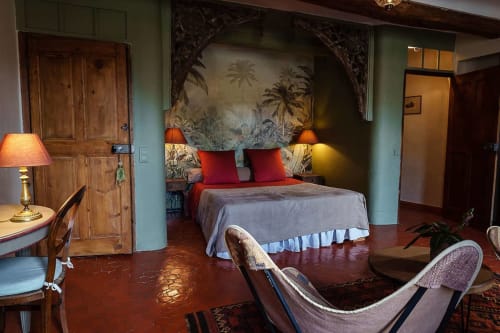 Geräumiges Schlafzimmer in La Bouscatière B&B in Moustiers-Sainte-Marie mit roten Kissen, tropischem Kopfteil und warmem Holz