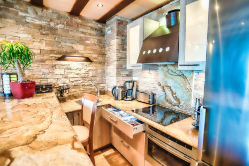 Cuisine moderne du gîte Banyuls-sur-Mer : plan de travail en granit, crédence en pierre et électroménagers inox