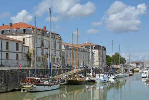Voiliers amarrés au port de Trizay avec bâtiments historiques en bord d'eau, Le Pirate Benèze