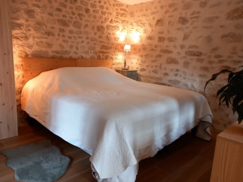 Chambre rustique en pierre à La Maison De Fleurat à Domeyrot, avec literie blanche, tête de lit en bois et ambiance chaleureuse