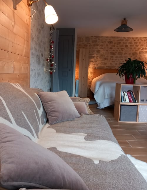 Chambre douillette à La Maison De Fleurat avec sièges confortables, décoration festive et murs en pierre rustique à Domeyrot