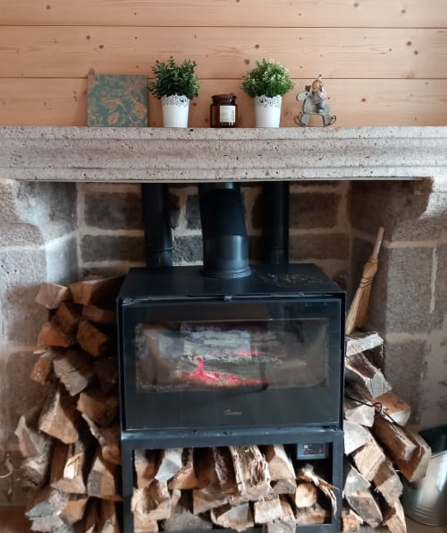 Foyer avec poêle de bois noir à La Maison De Fleurat, Domeyrot, manteau en béton et plantes en pot