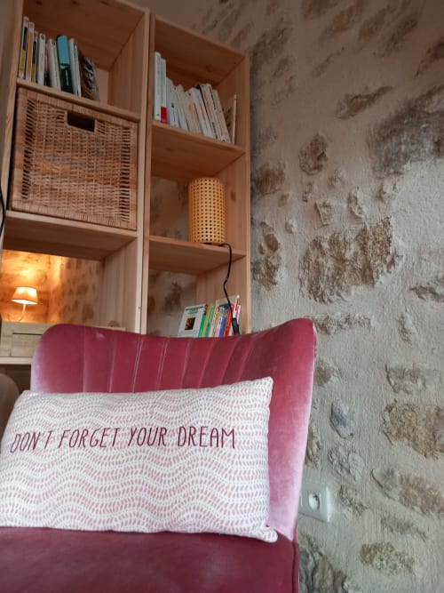 Chambre douillette à La Maison De Fleurat avec tête de lit en velours rose, coussin inspirant, étagères en bois avec livres et décoration