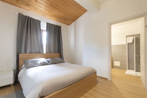Accessible double bedroom at B&B La Camia in Castel di Sangro with wooden bed, ensuite shower, and garden views