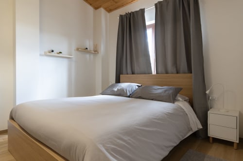 Accessible double bedroom at B&B La Camia with wooden bed, grey curtains, white walls, and modern furnishings in Castel di