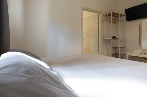 Modern accessible double bedroom at B&B La Camia in Castel di Sangro with white bedding, wardrobe, and garden view