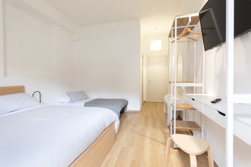 Bright modern triple bedroom at B&B La Camia in Castel di Sangro with wooden floors, white bedding, and minimalist décor