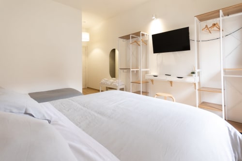 Modern bright bedroom at B&B La Camia in Castel di Sangro with white bed, TV, desk, and minimalist wood furnishings