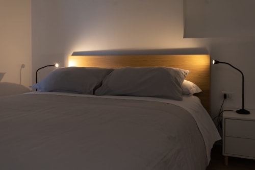 Modern bedroom at B&B La Camia in Castel di Sangro with wood-paneled headboard, ambient lighting, and dark bedding