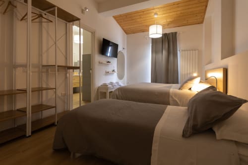 Triple room with two beds at B&B La Camia in Castel di Sangro, featuring TV, bathroom, and wooden ceiling details