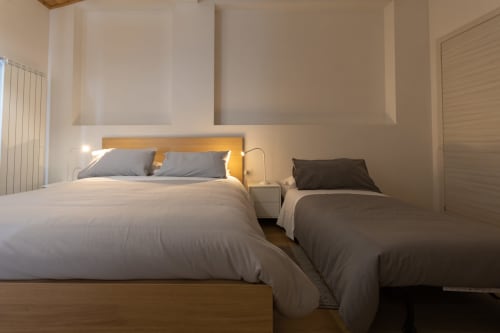 Modern bedroom at B&B La Camia in Castel di Sangro with queen bed and single bed, wooden headboard, and warm lighting
