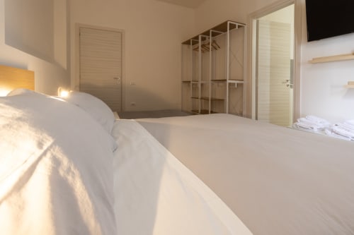Bright modern bedroom at B&B La Camia with twin beds, wooden wardrobe, and garden views in Castel di Sangro