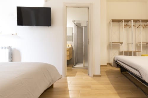 Quadruple room at B&B La Camia in Castel di Sangro with two beds, TV, wooden floors, and ensuite bathroom