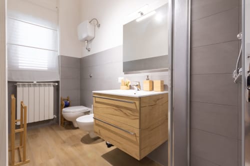 Modern bathroom in La Camia B&B with wooden vanity, white sink, toilet, and walk-in shower in Castel di Sangro