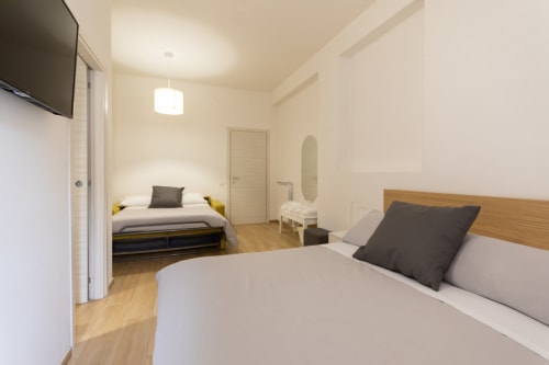 Spacious quadruple room at B&B La Camia in Castel di Sangro with two beds, wooden floors, and modern amenities