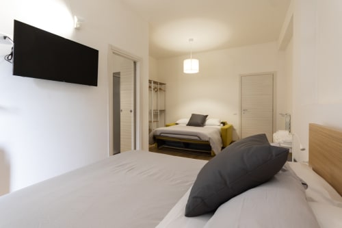Bright modern quadruple bedroom at B&B La Camia with two beds, flat-screen TV, and contemporary furnishings in Castel di