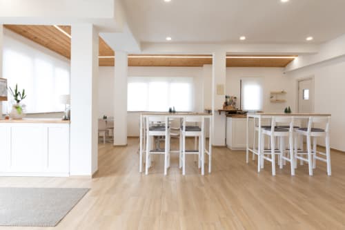 Bright, modern dining area at B&B La Camia in Castel di Sangro with wooden floors, white bar seating, and natural light
