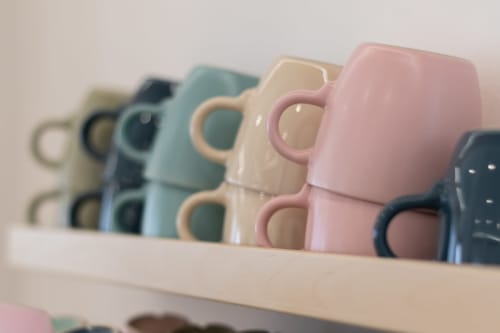 Colorful ceramic mugs lined on shelf at B&B La Camia, Castel di Sangro