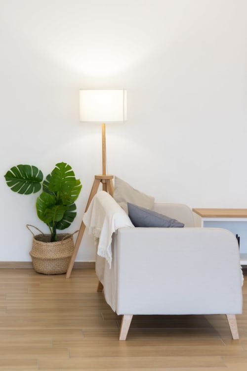 Modern living room at B&B La Camia with white armchair, wooden floor lamp, and green monstera plant in woven basket