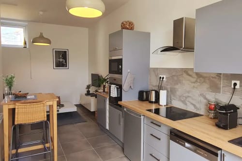 Cuisine moderne avec plans de travail en bois et coin repas dans un appartement à Beaune à la Conciergerie Des Climats