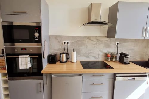 Cuisine moderne de l'appartement Beaune avec électroménagers inox, plan de travail bois et dosseret marbre à la Conciergerie