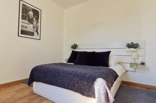 Chambre moderne à la Conciergerie Des Climats à Beaune avec literie sombre, tête de lit blanche, parquet et vue sur la ville