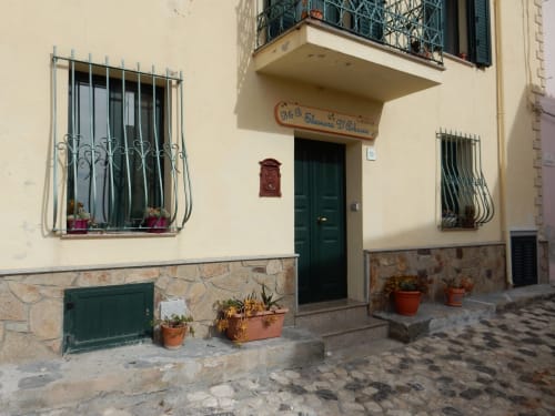 Ingresso del B&B Eleonora D'Arborea a Posada, Italia: porta verde, finestre con grate e vasi in terracotta