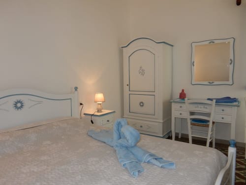 Camera accogliente al B&B Eleonora D'Arborea a Posada con arredi color crema, accenti blu e arte decorativa con asciugamani