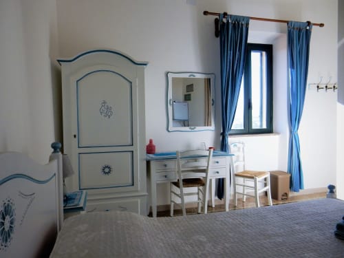 Camera da letto B&B Eleonora D'Arborea a Posada con armadio azzurro, scrivania e tende blu