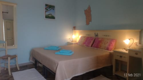 Bedroom at B&B Eleonora D'Arborea in Posada with bed, pink pillows, blue towels, and warm lighting
