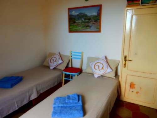 Camera doppia al B&B Eleonora D'Arborea a Posada con due letti singoli, cuscini numerati e quadri paesaggistici