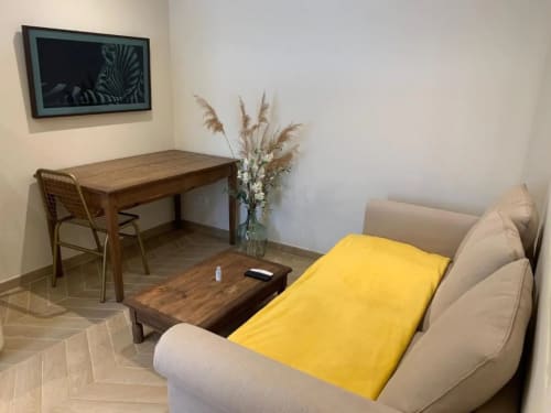 Appartement moderne à Beaune avec canapé beige, jeté jaune, bureau en bois, télévision et décoration herbes de pampa