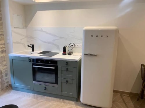 Kitchenette moderne à la Conciergerie Des Climats à Beaune avec réfrigérateur blanc SMEG, mobilier vert et crédence en marbre