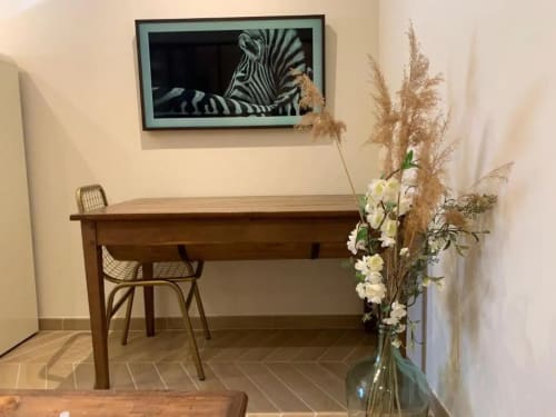 Coin bureau de l'appartement à Beaune avec table en bois, chaise, téléviseur affichant un zèbre, et composition florale blanche