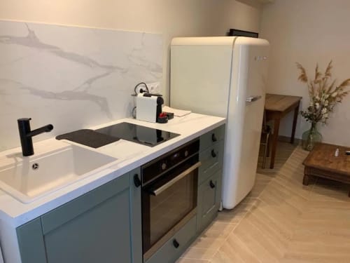 Cuisine moderne dans un appartement à Beaune avec plan de travail blanc, évier, four et réfrigérateur crème