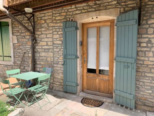Entrée en pierre de la Conciergerie Des Climats à Beaune avec volets vert menthe, porte en bois et coin détente