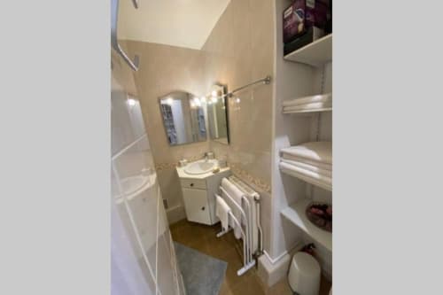 Salle de bains immaculée à la Conciergerie Des Climats à Beaune avec lavabo, miroir, porte-serviettes et rangements