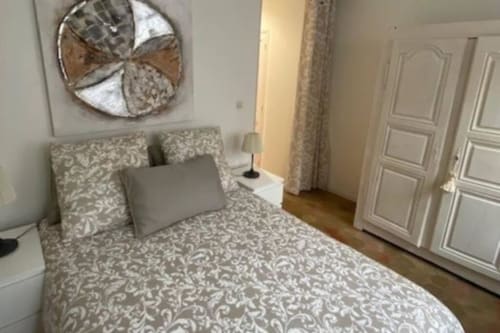 Chambre élégante à la Conciergerie Des Climats à Beaune avec parure décorée, art mural, armoire blanche et mobilier bois