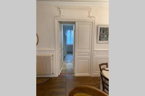 Élégant couloir de l'appartement de Beaune avec portes blanches, parquets et décoration classique à la Conciergerie Des Climats