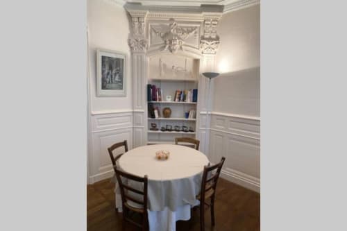 Élégante salle à manger à la Conciergerie Des Climats à Beaune avec table ronde, chaises classiques, bibliothèques intégrées et ornements raffinés