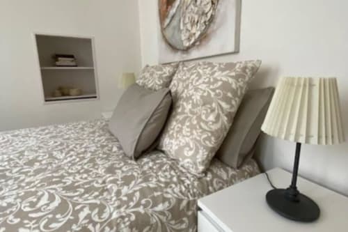 Chambre élégante à la Conciergerie Des Climats à Beaune avec literie motifs, lampe de bureau et étagères murales
