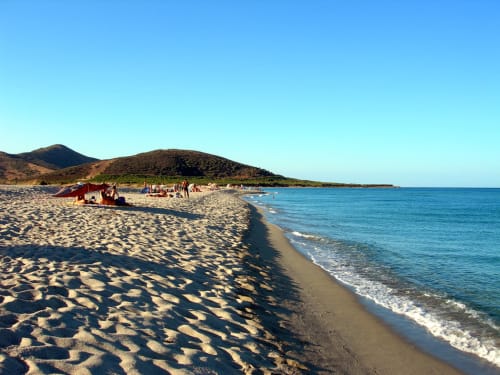 Spiaggia sabbiosa con acque cristalline e colline vulcaniche vicino al B&B Eleonora D'Arborea, Posada Italia