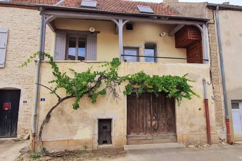 Charmante villa en pierre à Beaune avec façade couverte de lierre, portes en bois et balcon à l'étage, partie de la Conciergerie Des