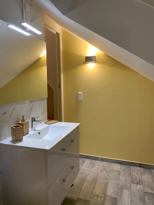 Salle de bain contemporaine aux murs jaunes, vasque blanche et équipements élégants à la villa Conciergerie Des Climats à Beaune